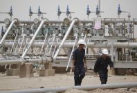 Workers walk at Rumaila oilfield in Basra, 420 km (260 miles) southeast of Baghdad
