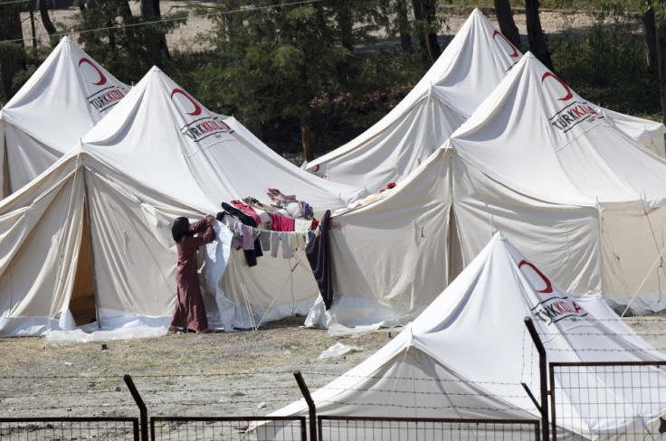 A woman rolls up a tent flap in a refugee camp in the Turkish border town of Yayladagi in Hatay province