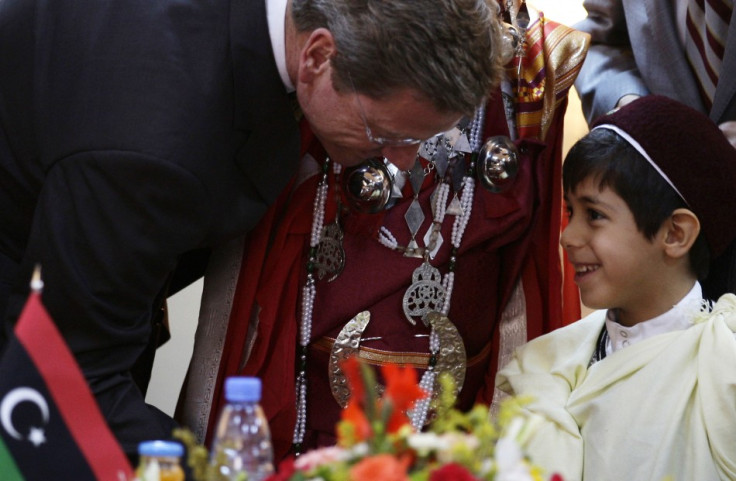 German Foreign Minister Guido Westerwelle shakes hands with a Libyan boy in traditional clothes after a news conference in Benghazi