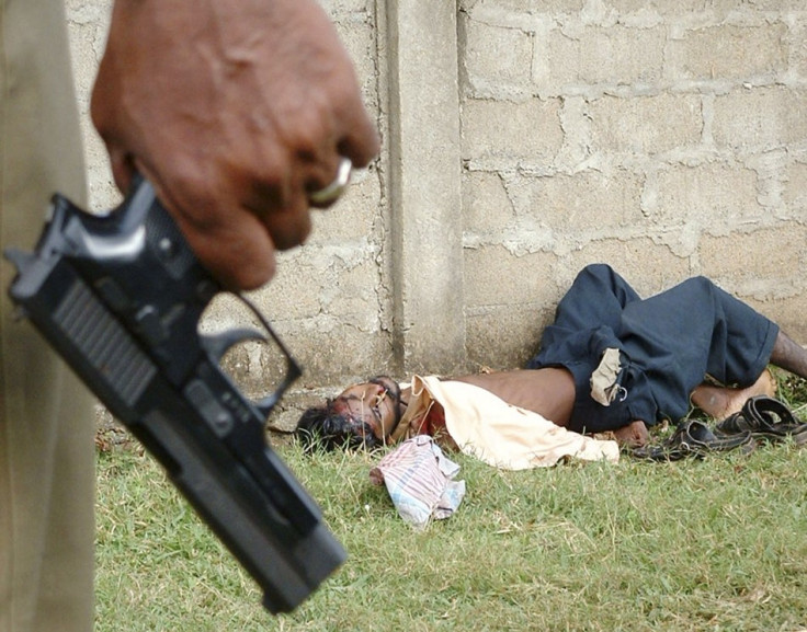 Police officer holds pistol near body of unidentified ethnic Tamil in Vavuniya