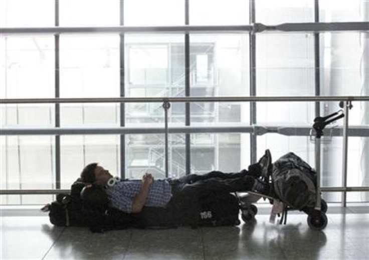 A passenger lays on luggage at Terminal 5 in Heathrow Airport