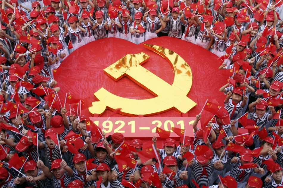 Students wave flags of the CPC as they pose for a photo with an emblem of the CPC at a primary school in Zaozhuang, Shandong province