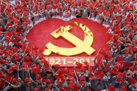 Students wave flags of the CPC as they pose for a photo with an emblem of the CPC at a primary school in Zaozhuang, Shandong province