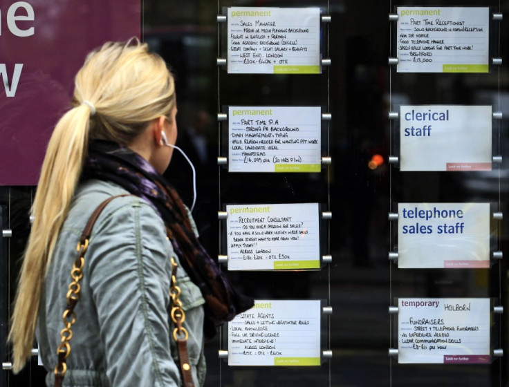 A woman passes notices for jobs in the window of a recruitment agency.