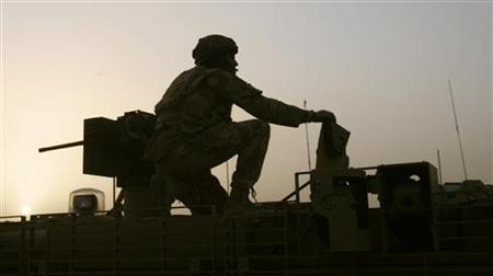 A British soldier is seen holding on to the turret gun of a manoeuvring armoured vehicle in Lashkar Gah