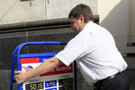An employee places a board displaying currency rates outside a bank in the capital Minsk
