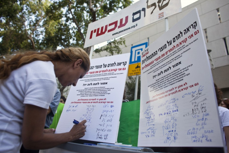 A woman signs a Peace Now petition in Tel Aviv, calling for a boycott of settlement products
