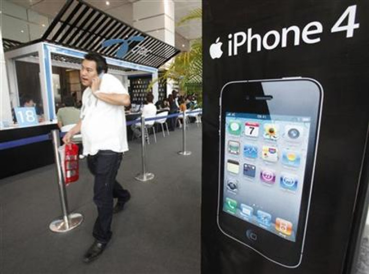 A man walks past an advertisement for an iPhone 4 displayed at a shop in Bangkok