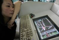 A woman watches the Shanghai Composite Index on computer screen in Shanghai