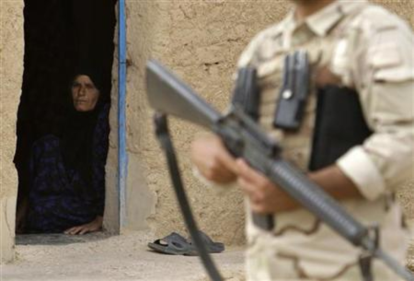A woman looks at an Iraqi soldier standing guard
