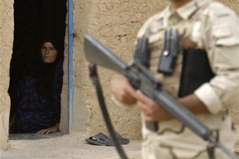 A woman looks at an Iraqi soldier standing guard