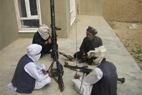 Taliban fighters pose with weapons as they sit in their compound at an undisclosed location in southern Afghanistan