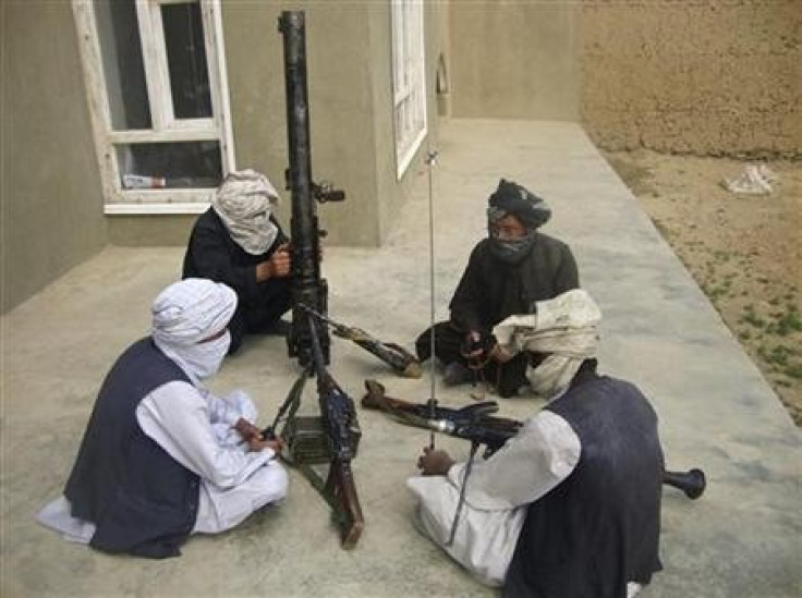Taliban fighters pose with weapons as they sit in their compound at an undisclosed location in southern Afghanistan