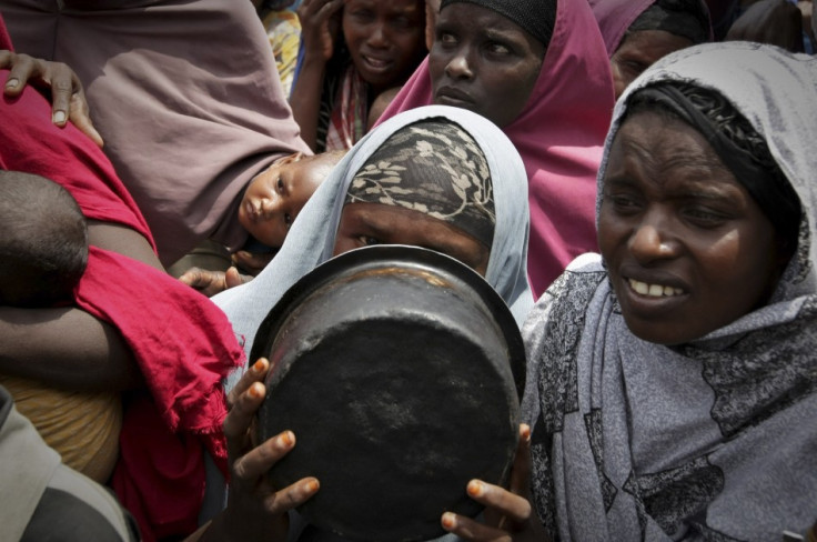 A woman covers her face with a cooking pot as she queues for food in a camp established by the Somali Transitional Federal Government for the internally displaced people in Mogadishu