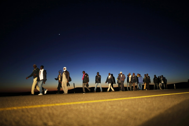 African migrants walk on a road after choosing to permanently leave their open detention facility