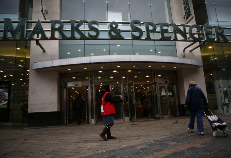 A woman sells copies of the Big Issue outside a Marks and Spencer supermarket.