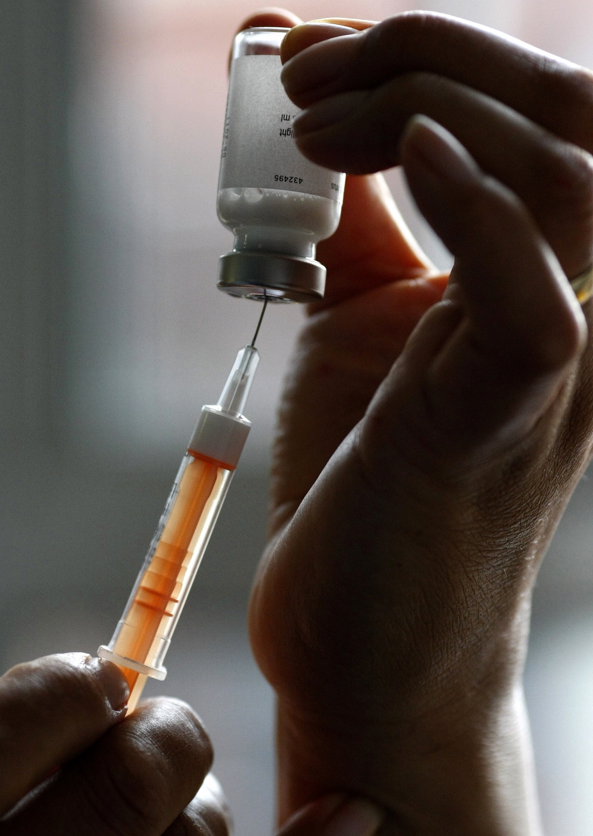 A flu vaccination is drawn into a syringe. A flu vaccination is drawn into a syringe.