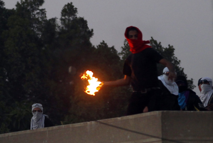 A masked student of Al-Azhar University throws a Molotov cocktail at riot police and residents during clashes outside the university campus in Cairo