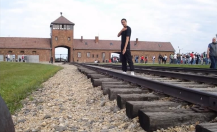 A young man performs the gesture outside Auschwitz concentration camp. (YouTube)