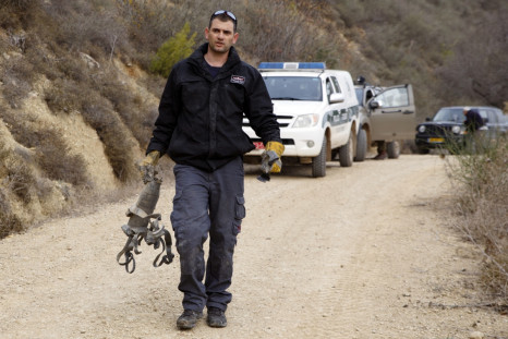 An Israeli police explosive expert carries the remains of a rocket after it landed near the northern town of Kiryat Shmona December