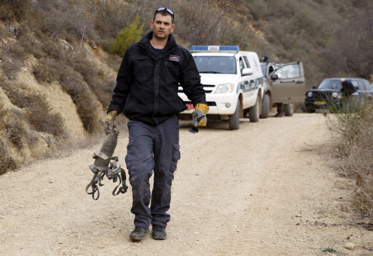 An Israeli police explosive expert carries the remains of a rocket after it landed near the northern town of Kiryat Shmona December