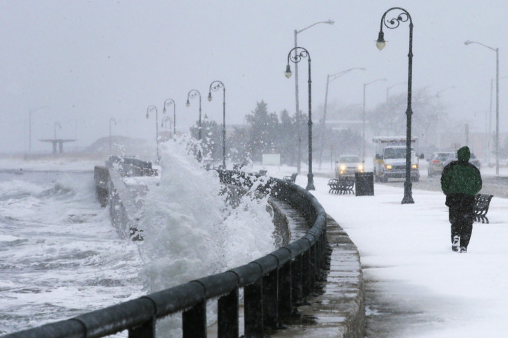 A man jogs past waves crashing against the seawall around high tide during a winter nor'easter snowstorm in Lynn, Massachusetts January 2, 2014.