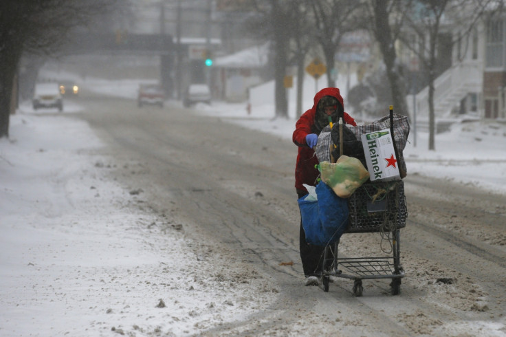 A man pushes a cart up the road while scavenging for bottles and cans during the storm.