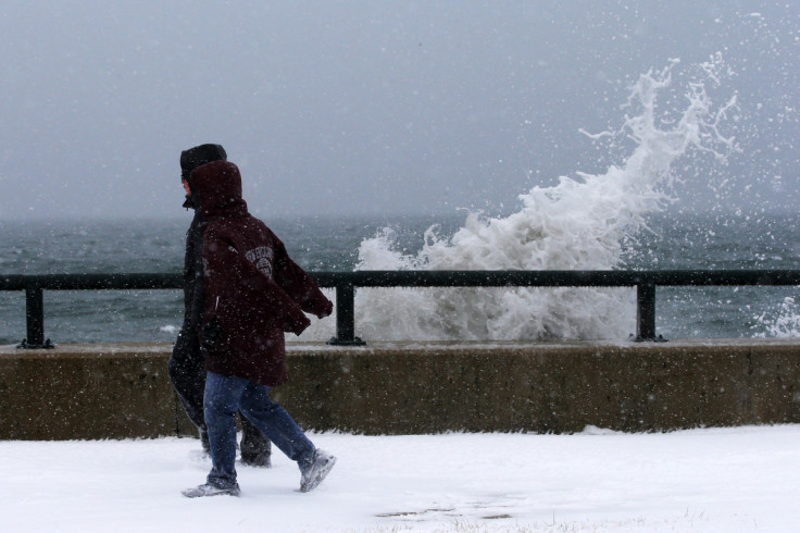 Onlookers walk past waves crashing against the seawall around high tide in Lynn following the storm.