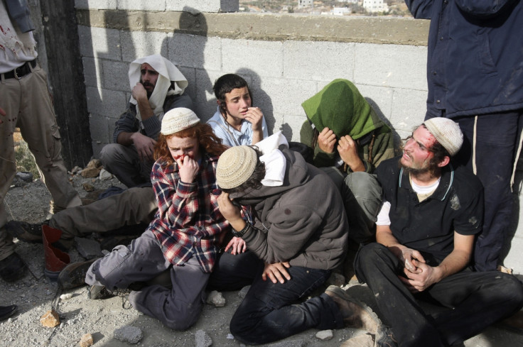 Jewish settlers sit together after being detained by Palestinian villagers