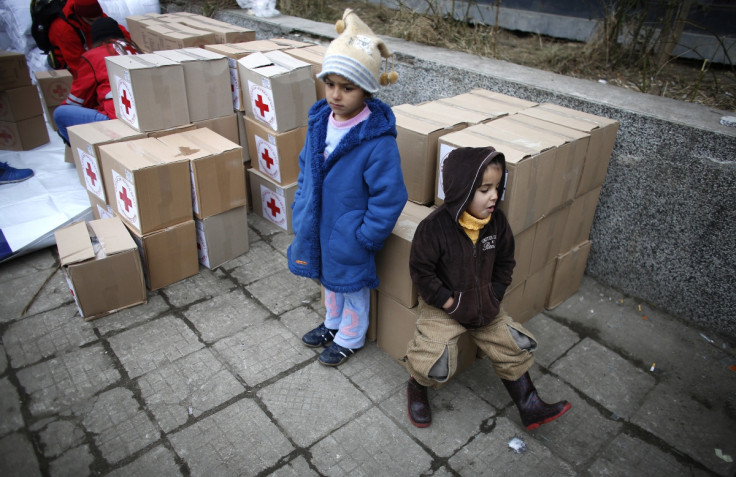 Syrian refugee children sit on boxes with humanitarian aid before its distribution by volunteers of the Bulgarian Red Cross