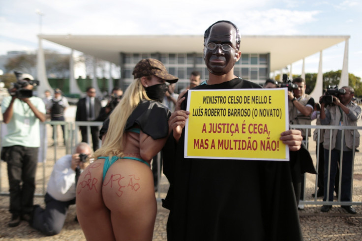 Protesters, dressed as President of Supreme Court Joaquim Barbosa and singer MC Bandida, pose as they protest in front of the Federal Supreme Court of Brazil during the 'mensalao' corruption trials.  The poster reads, "Minister Celso de Mello and Luis 