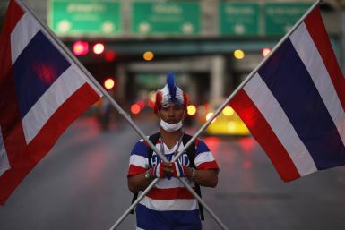 An anti-government protester in the colours of Thailand's national flag arrives to block one of city's the key intersections