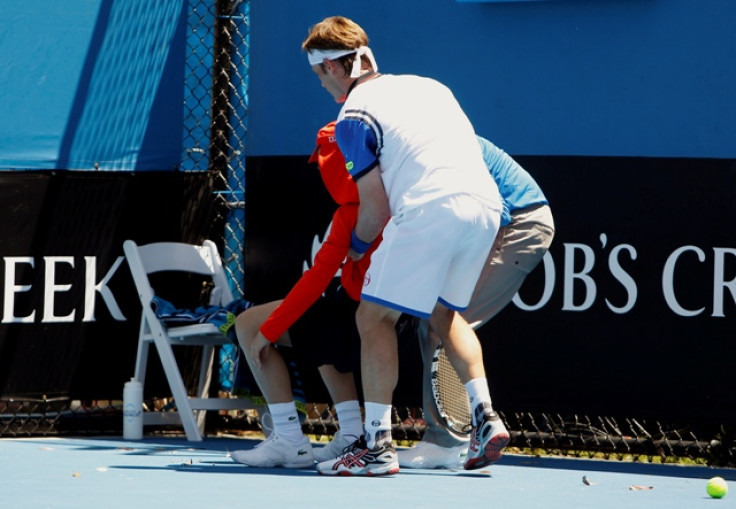 Daniel Gimeno-Traver (front) of Spain assists an official in helping a ball boy who collapsed during his men's singles match against Milos Raonic of Canada at the Australian Open 2014 tennis tournament in Melbourne