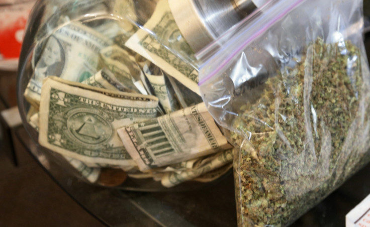 A bag of marijuana being prepared for sale sits next to a money jar at BotanaCare in Northglenn, Colorado