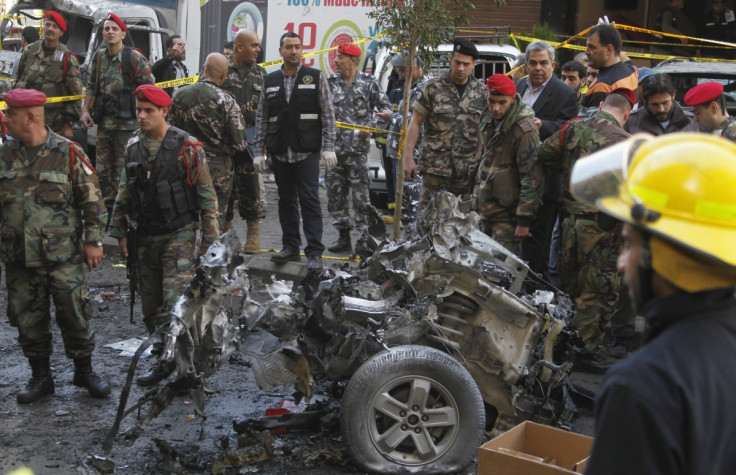 Lebanese army soldiers examine a burnt car at the site of an explosion in the Haret Hreik area