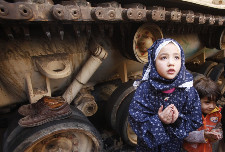 A girl attends Friday prayers in front of an army tank in Tahrir Square in Cairo