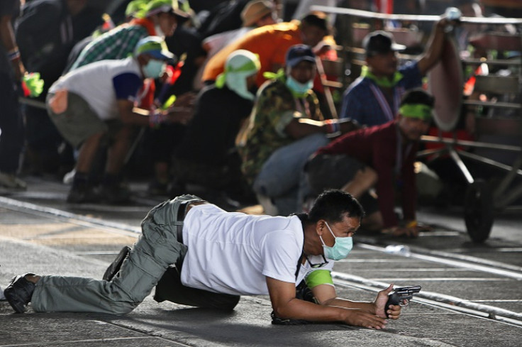 An anti-government protester crawls with a pistol during a gunfight with supporters of the ruling Puea Thai Party.