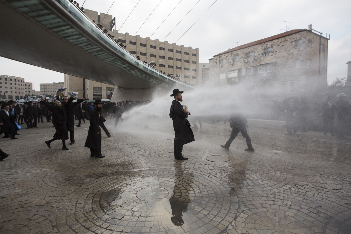 Ultra-Orthodox Jewish protesters are sprayed with a water cannon by Israeli policemen during a demonstration in Jerusalem