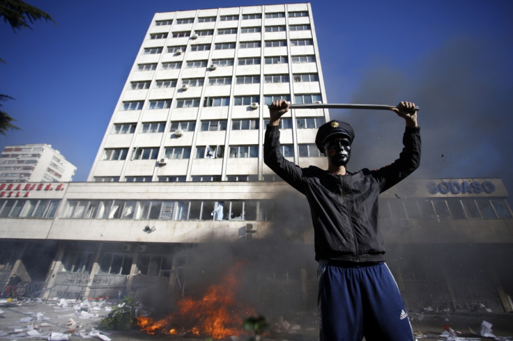 A protester stands near a fire set in front of a government building in Tuzla