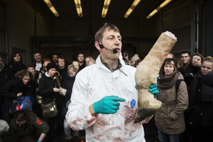 People look on as a veterinarian holds a leg of the giraffe Marius while it was being dismembered in Copenhagen Zoo February 9, 2014.