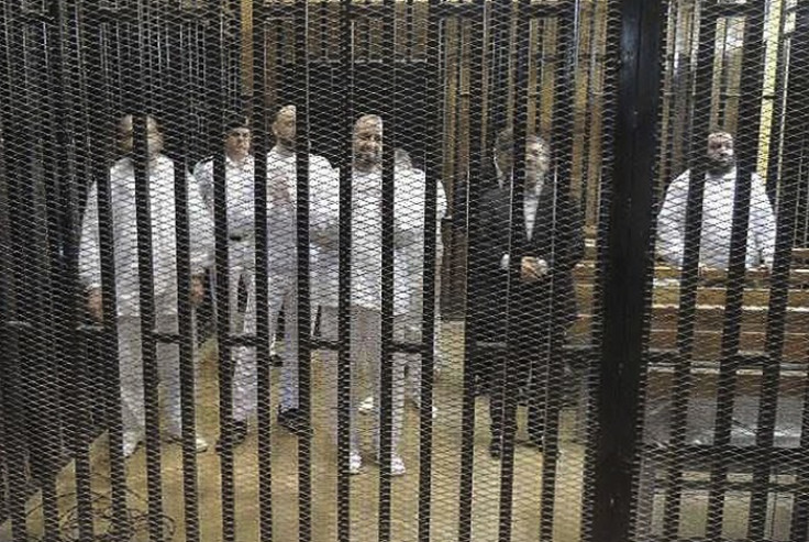 Mohamed Morsi (R) stands with other senior figures of the Muslim Brotherhood in a cage in a courthouse on the first day of their trial.