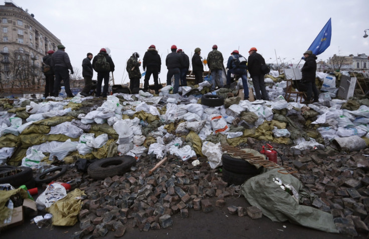 Anti-government protesters look out from a barricade in Kiev