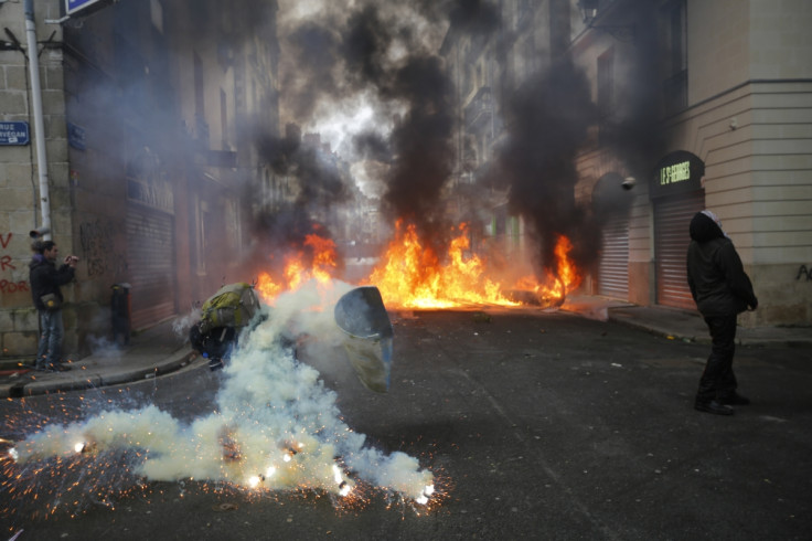 A tear gas grenade explodes near a masked protester