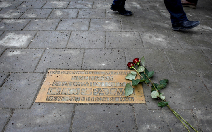 Pedestrians walk past a plaque marking the location where Swedish Prime Minister Olof Palme was shot and killed