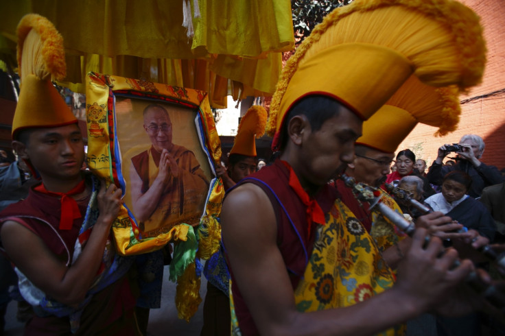 Tibetan monks carry a portrait of their spiritual leader Dalai Lama while performing rituals