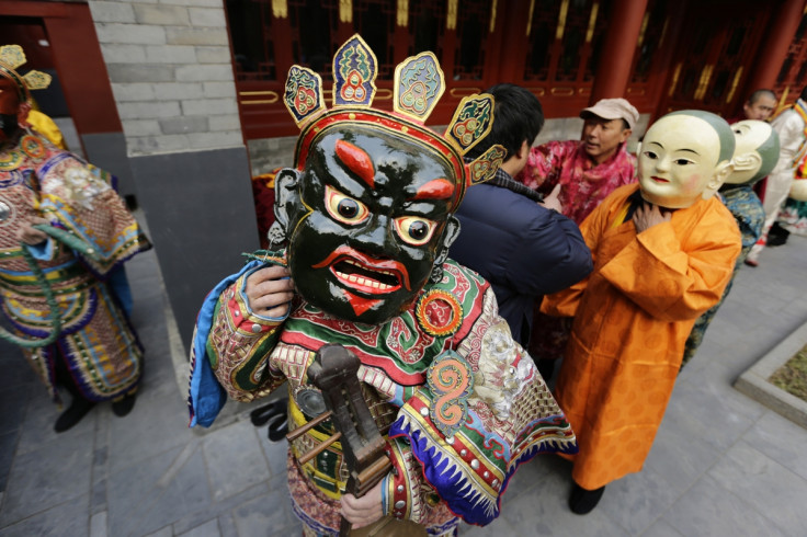 A Tibetan monk adjusts his mask while preparing for a religious ceremony, known as "Da Gui" or beating ghost