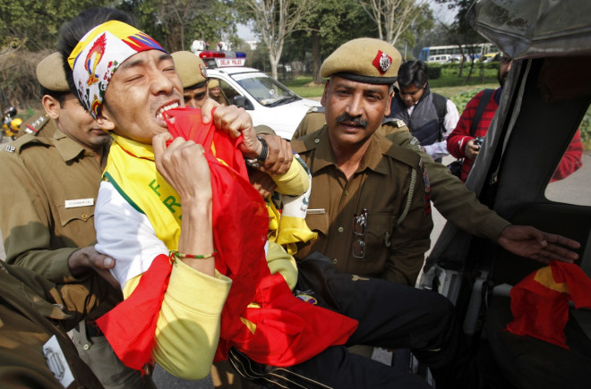 A Tibetan exile rips into a Chinese flag as he is detained by police during a protest in front of the Chinese embassy in New Delhi A Tibetan exile rips into a Chinese flag as he is detained by police during a protest in front of the Chinese embassy in New Delhi
