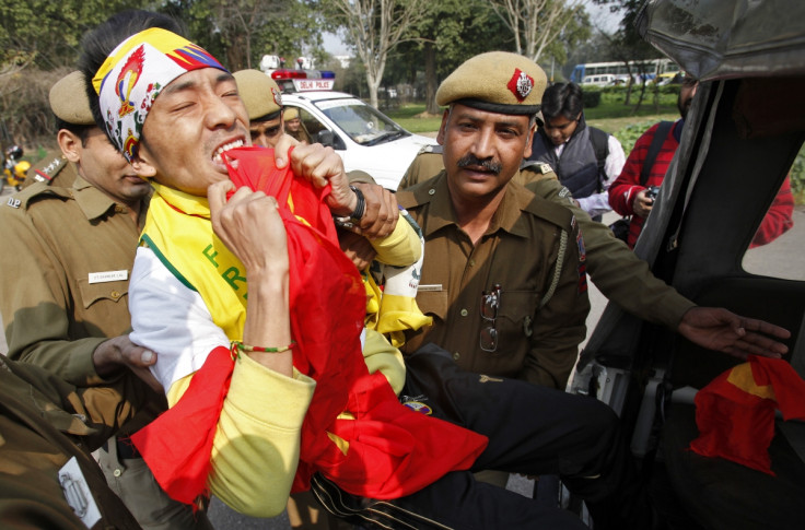 A Tibetan exile rips into a Chinese flag as he is detained by police during a protest in front of the Chinese embassy in New Delhi