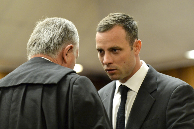 Oscar Pistorius consults with his lawyer Barry Roux on day one of his trial for killing Reeva Steenkamp