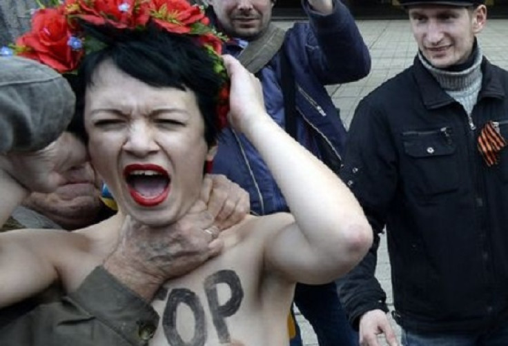 A bare breasted Femen activist is throttled during clashes between the radical feminists and paramilitary forces in Simferpol
